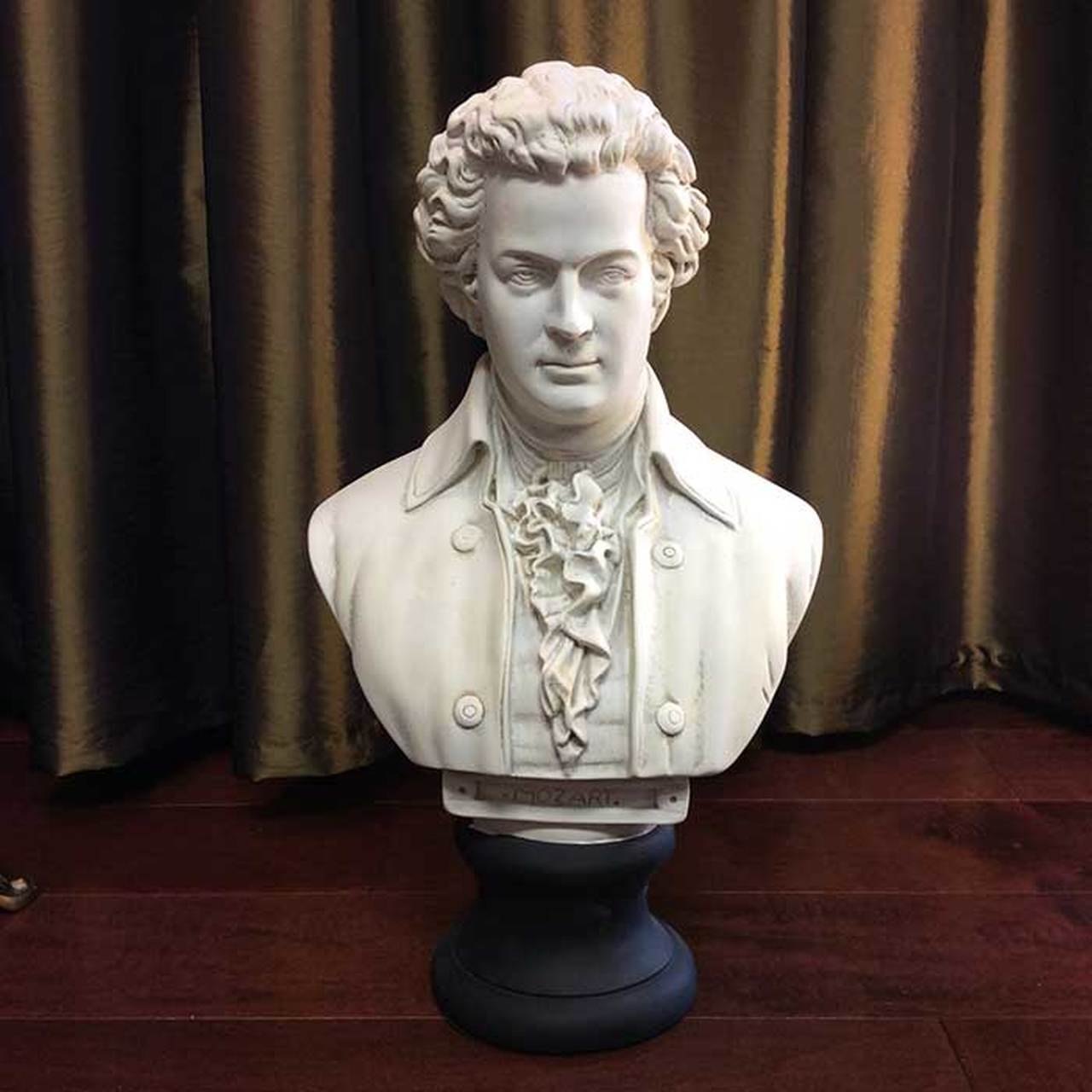A bust of Mozart in front of a gold curtain