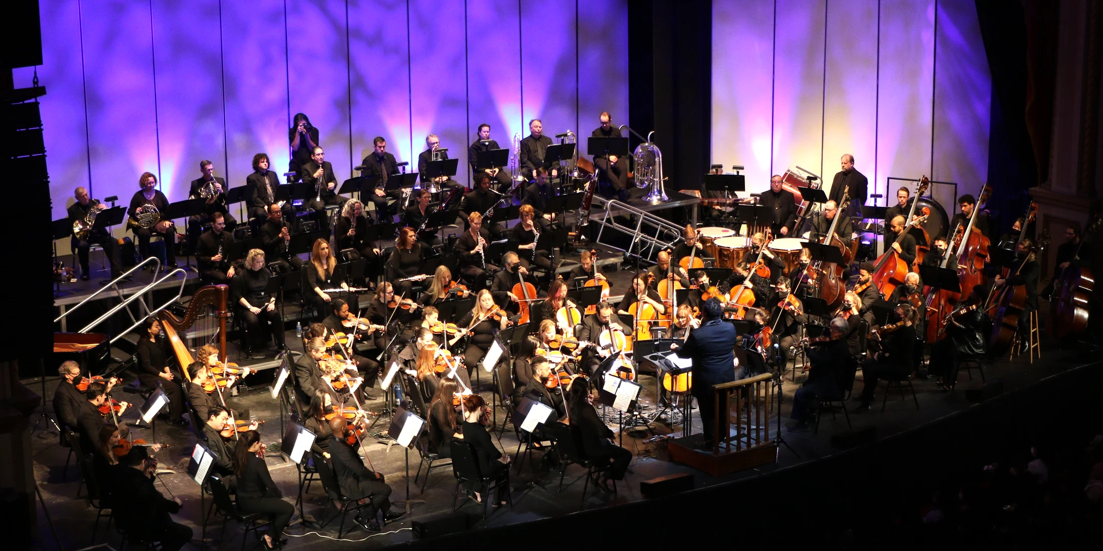 The San Bernardino Symphony in full performance beneath vivid blue and violet stage lighting