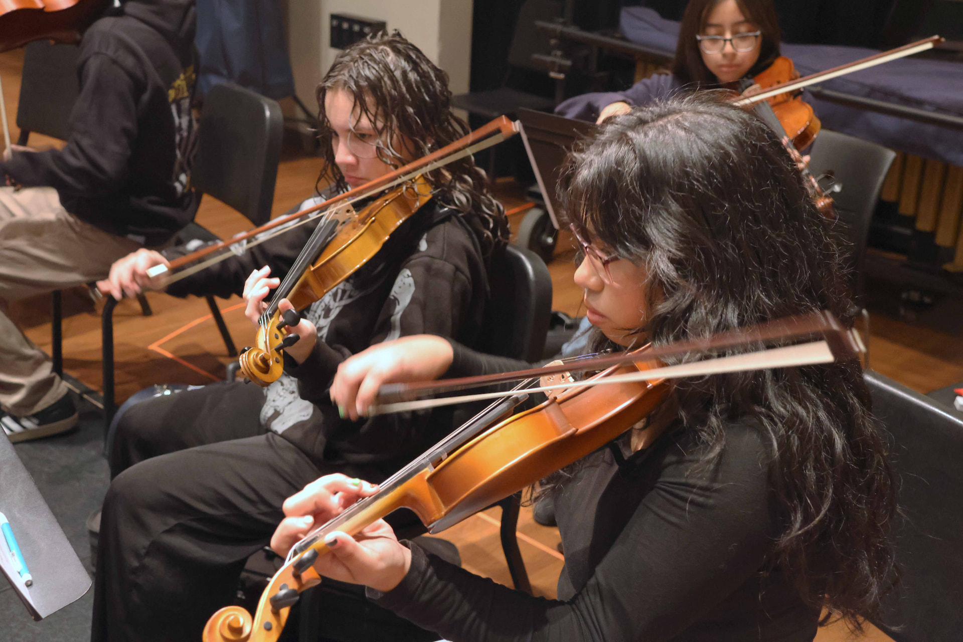 String students rehearsing in a wood-floored rehearsal hall