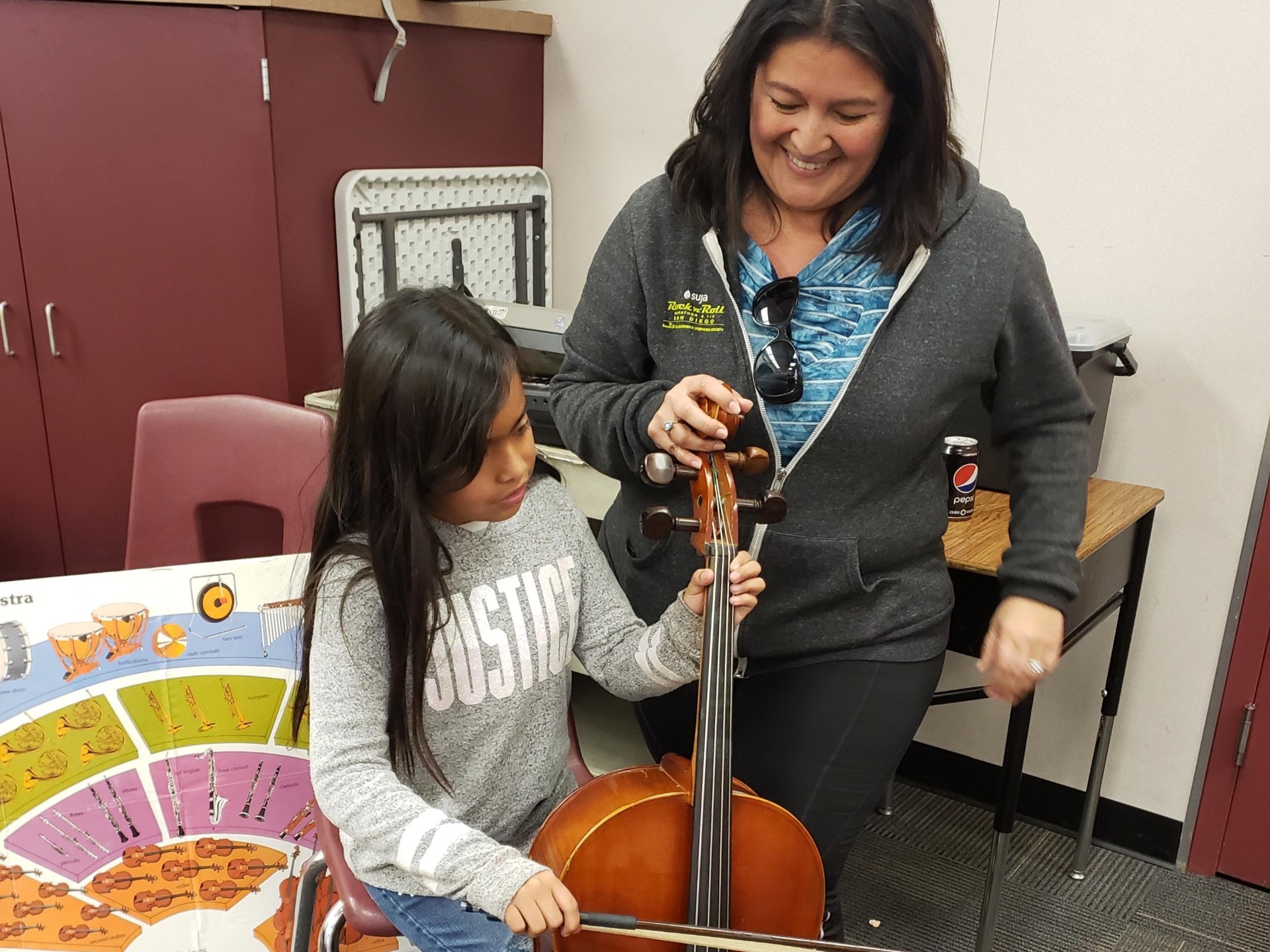 A young student explores a cello with an adult's guidance